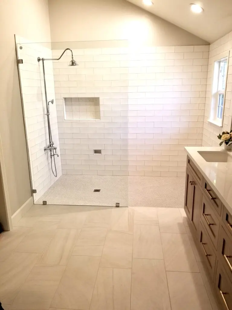 A bathroom with white tile and wood cabinets.