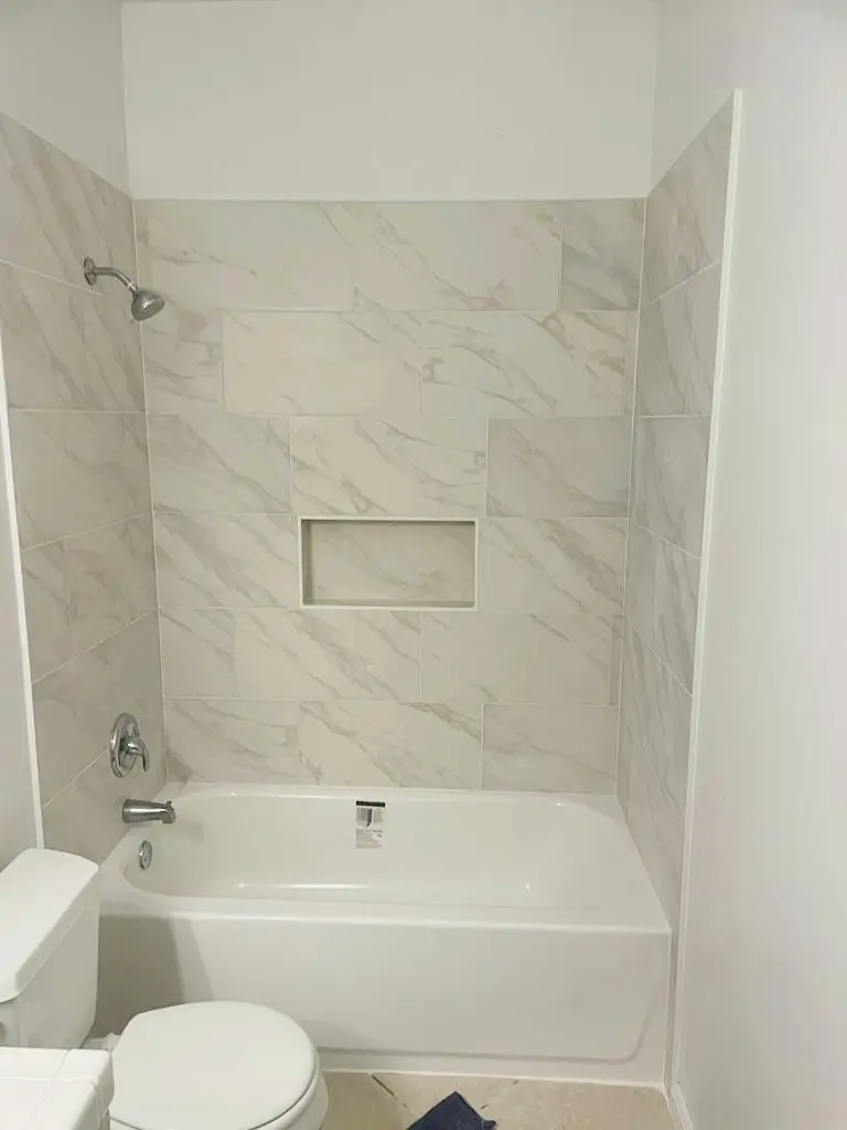 A bathroom with marble tile and white walls.