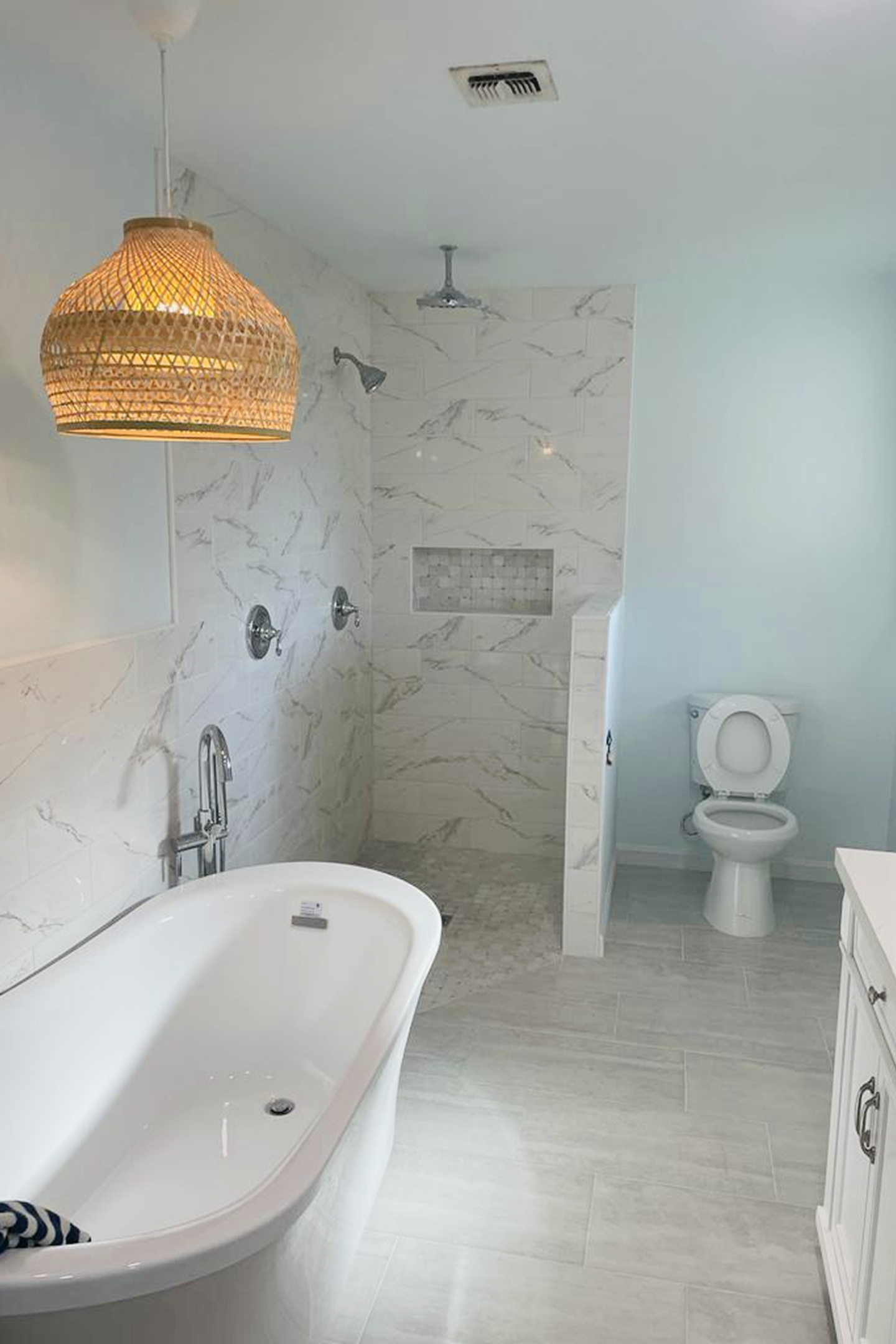 A bathroom with a tub, toilet and shower.