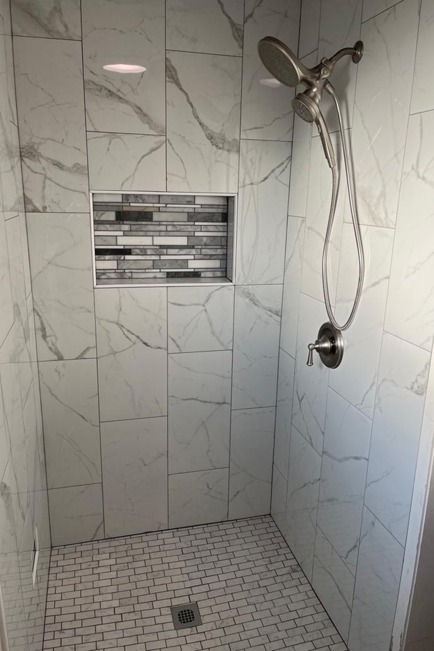 A bathroom with white tile and marble walls.