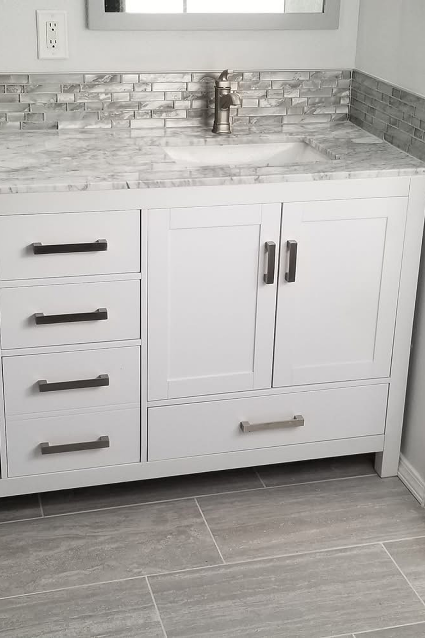 A bathroom vanity with marble counter top and white cabinets.
