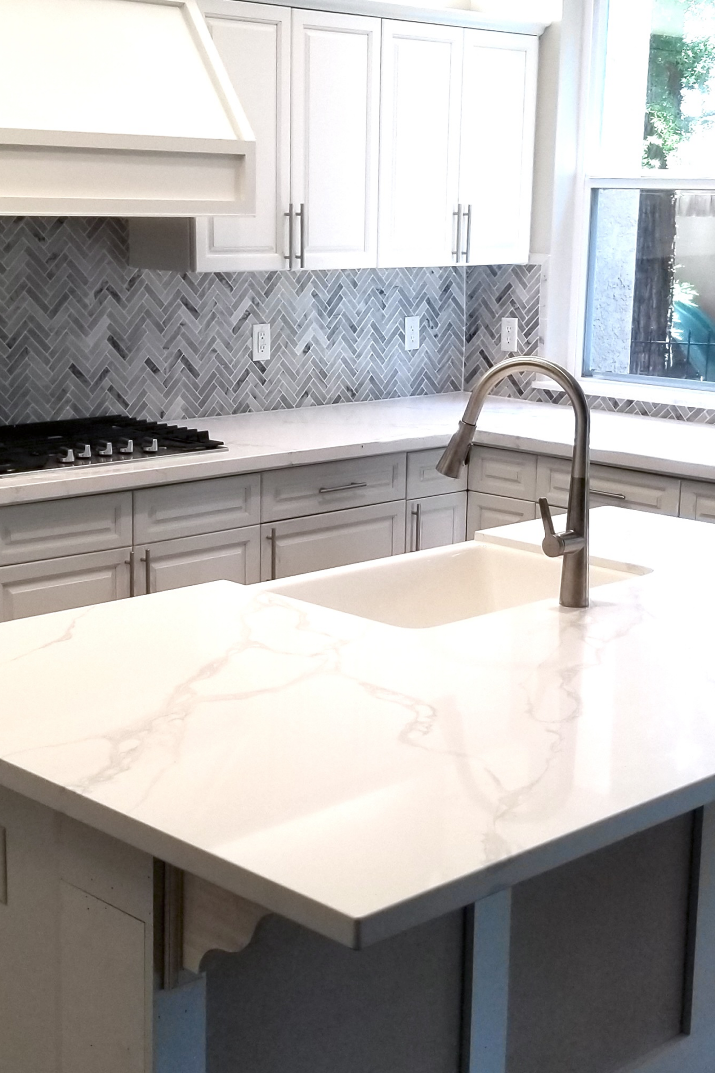 A kitchen with white cabinets and marble counter tops.