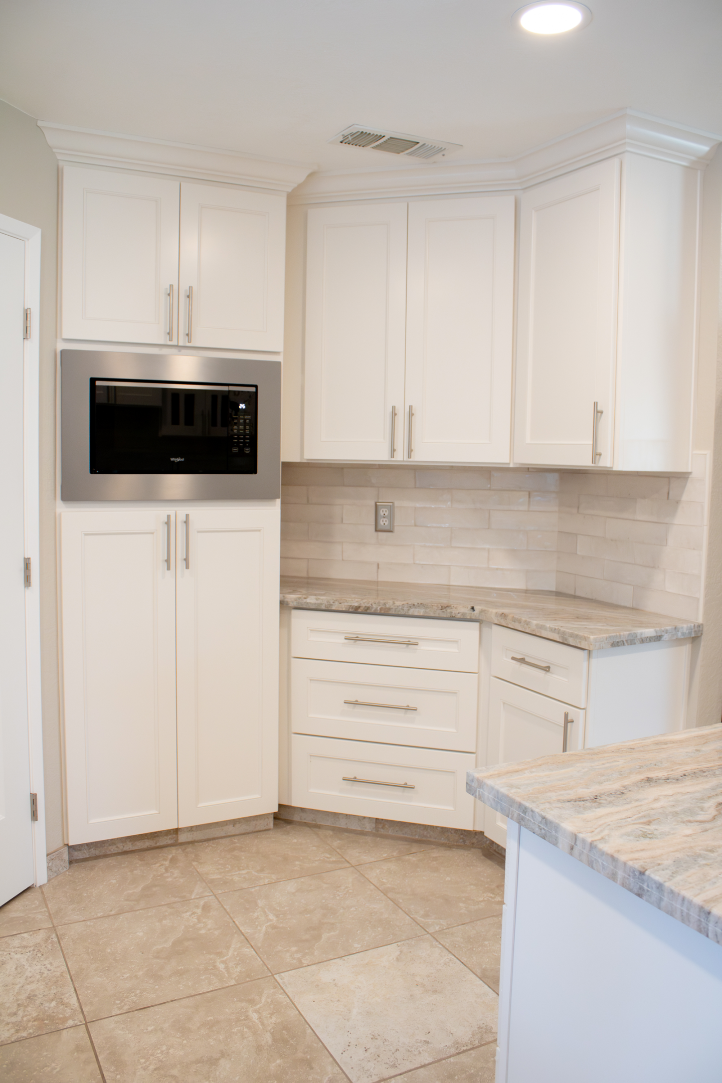 A kitchen with white cabinets and granite counter tops.