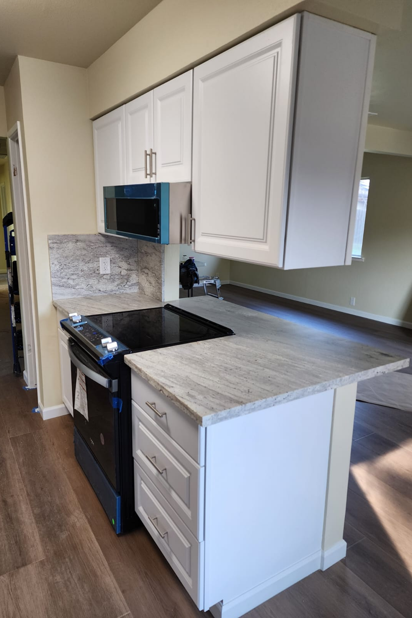 A kitchen with white cabinets and black appliances.
