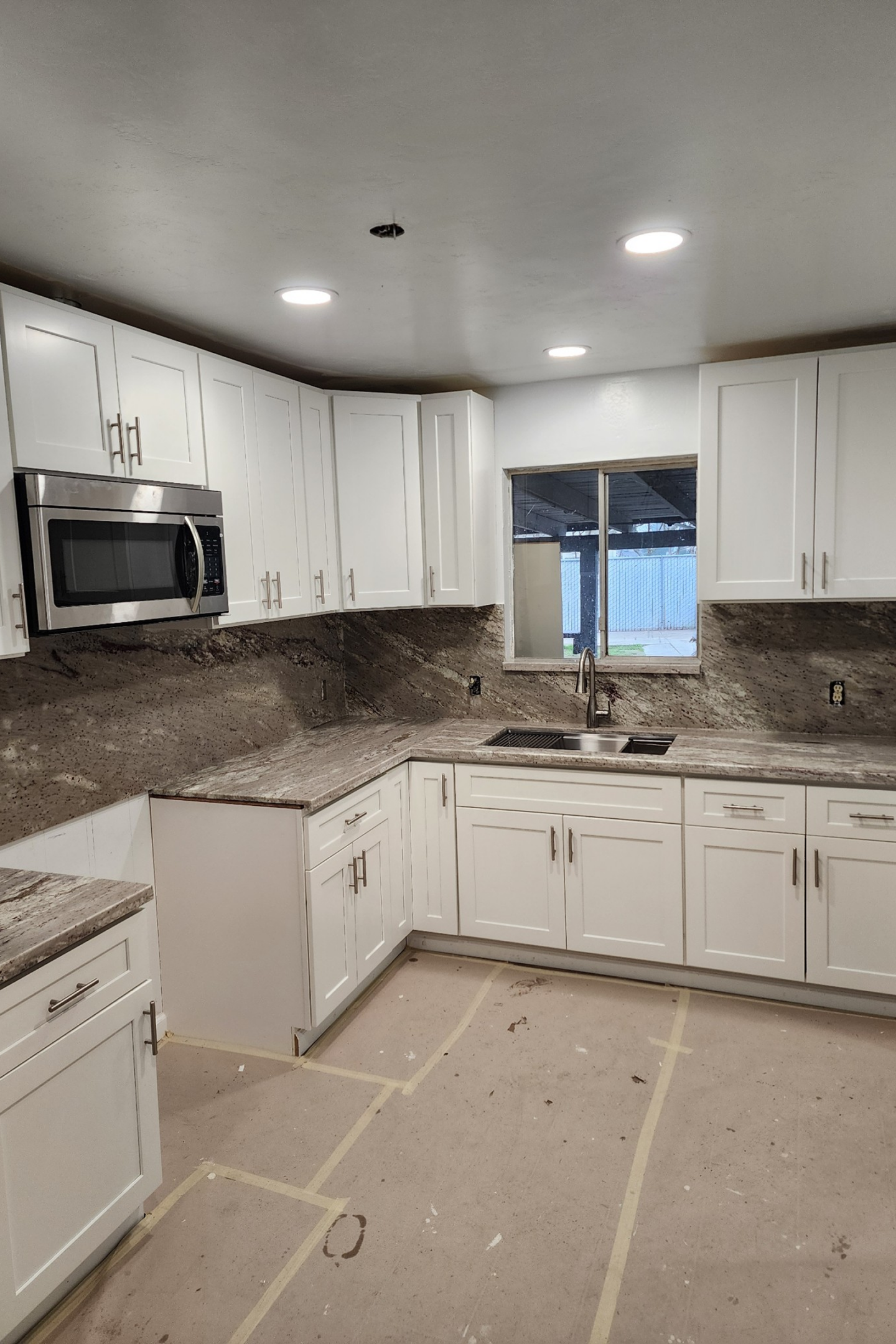 A kitchen with white cabinets and marble countertops.