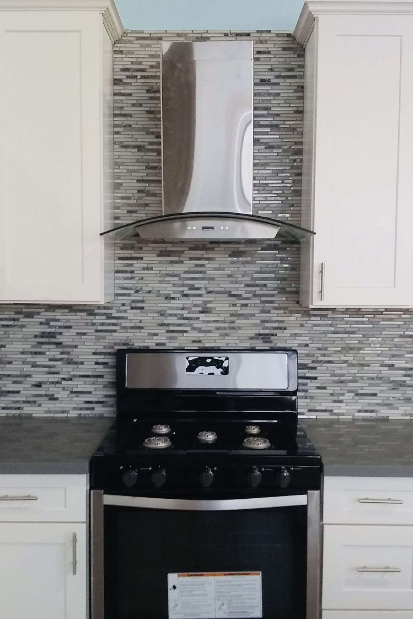 A stove with the hood up in a kitchen.