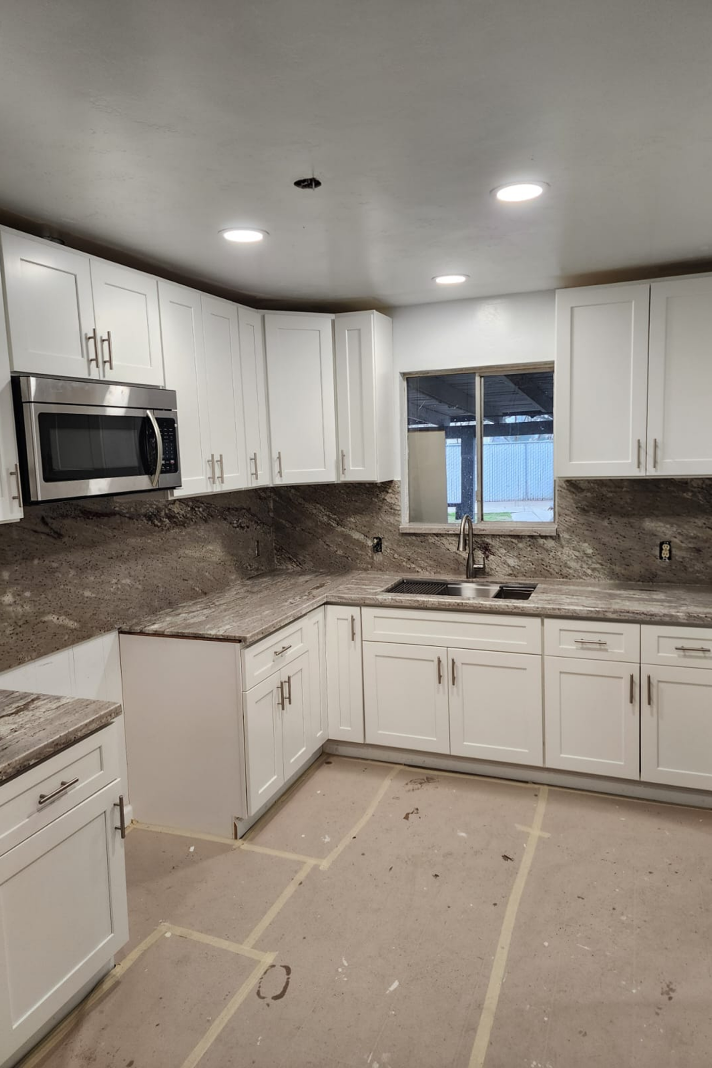 A kitchen with white cabinets and marble countertops.