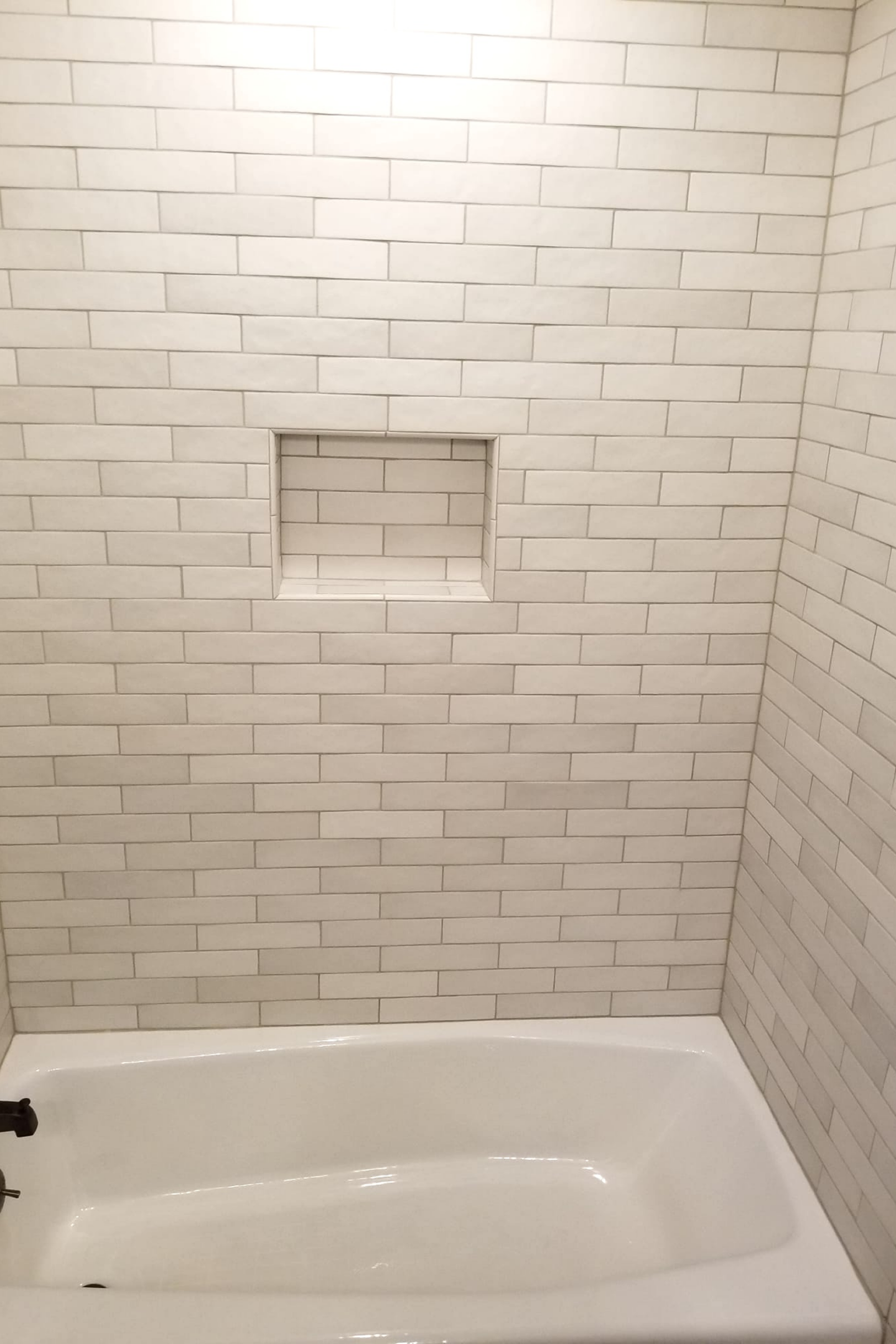 A white tiled bathroom with a bathtub and shower.