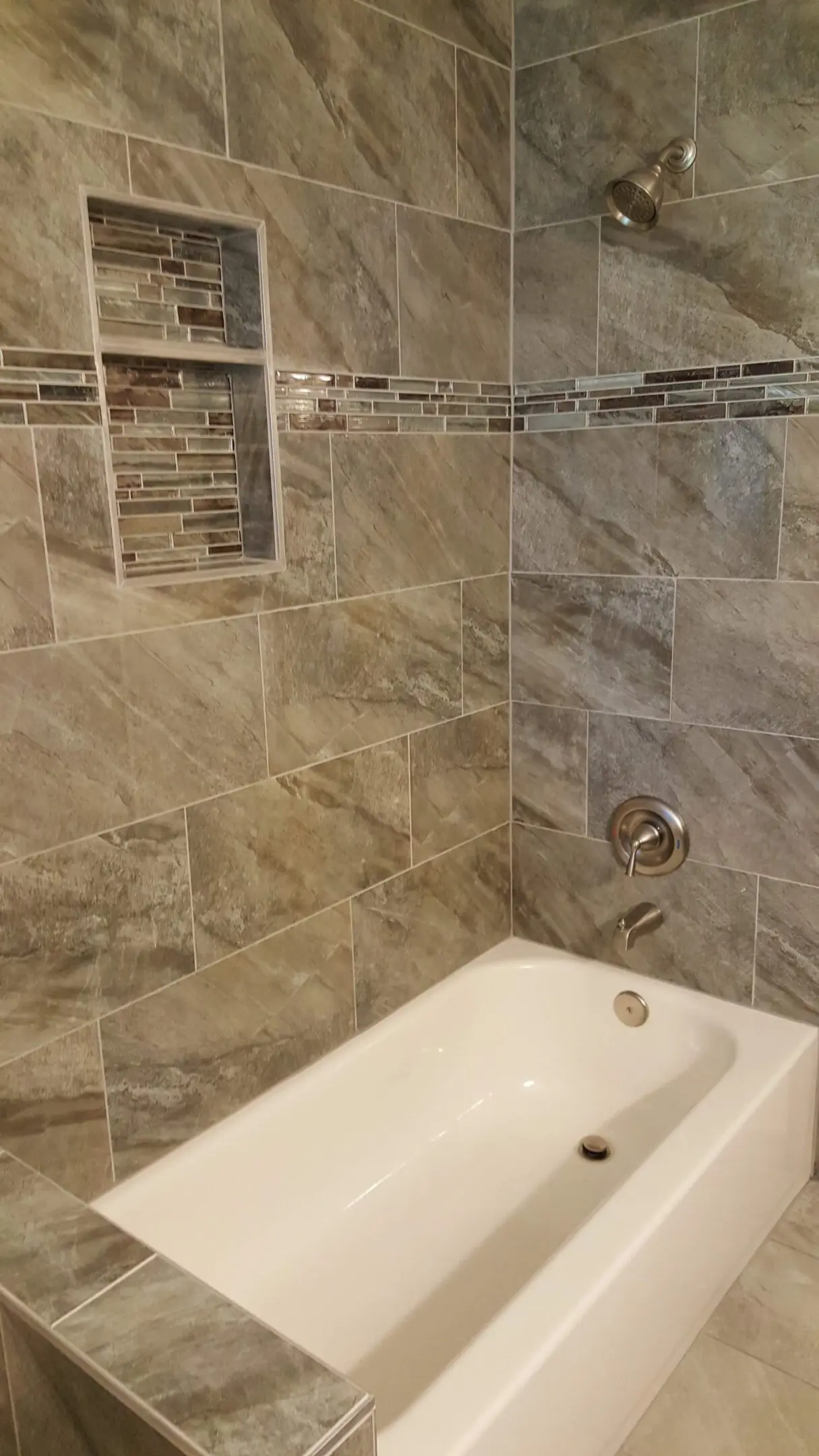 A bathroom with a tub and tiled walls.