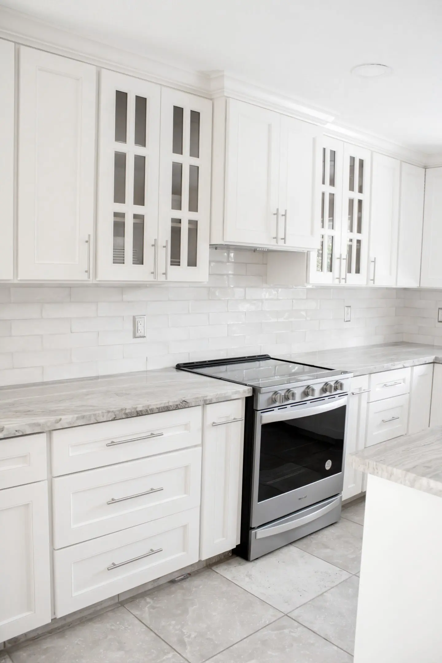 kit A kitchen with white cabinets and marble countertops.